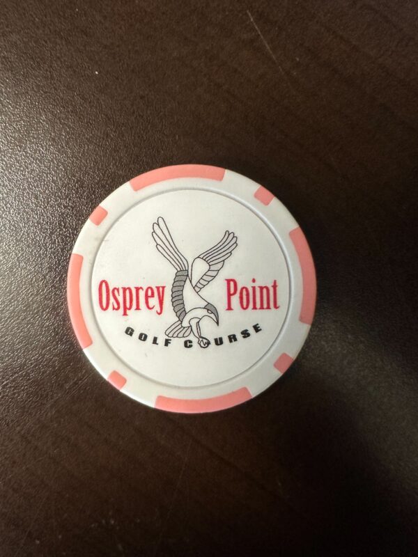 A white and red poker chip sitting on top of a table.