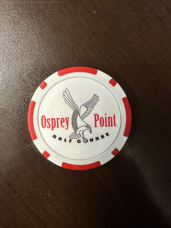 A red and white poker chip sitting on top of a table.