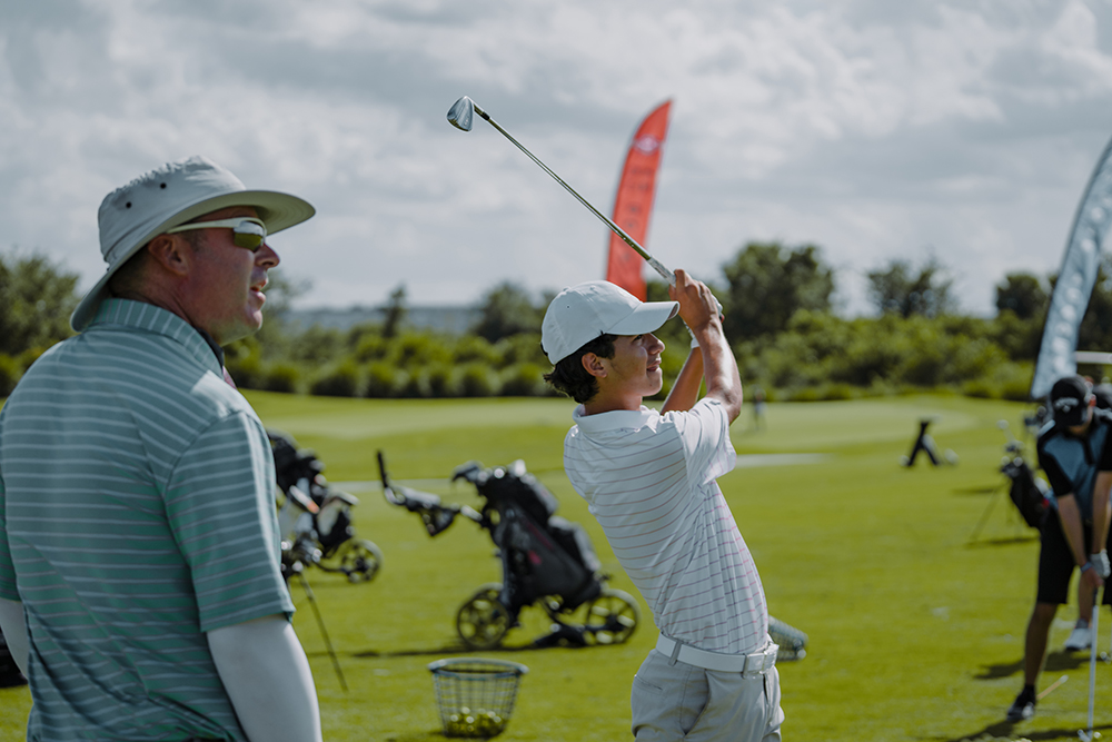 A man holding onto the golf club while another man watches.