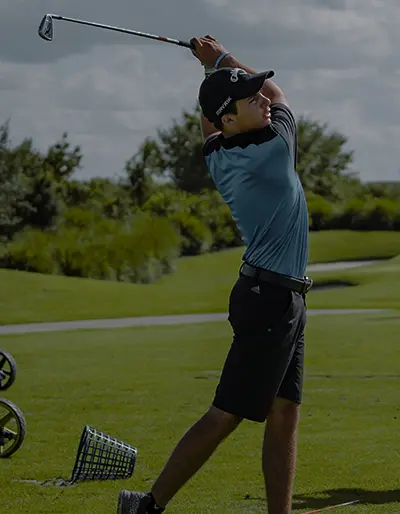 A man is swinging at the golf ball