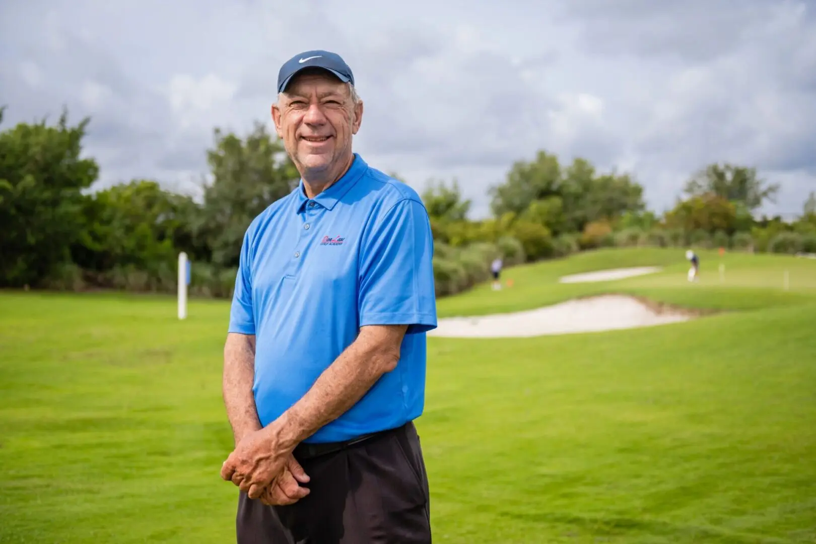 A man in blue shirt standing on grass field.