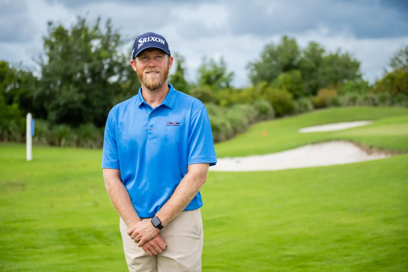 A man in blue shirt standing on grass field.