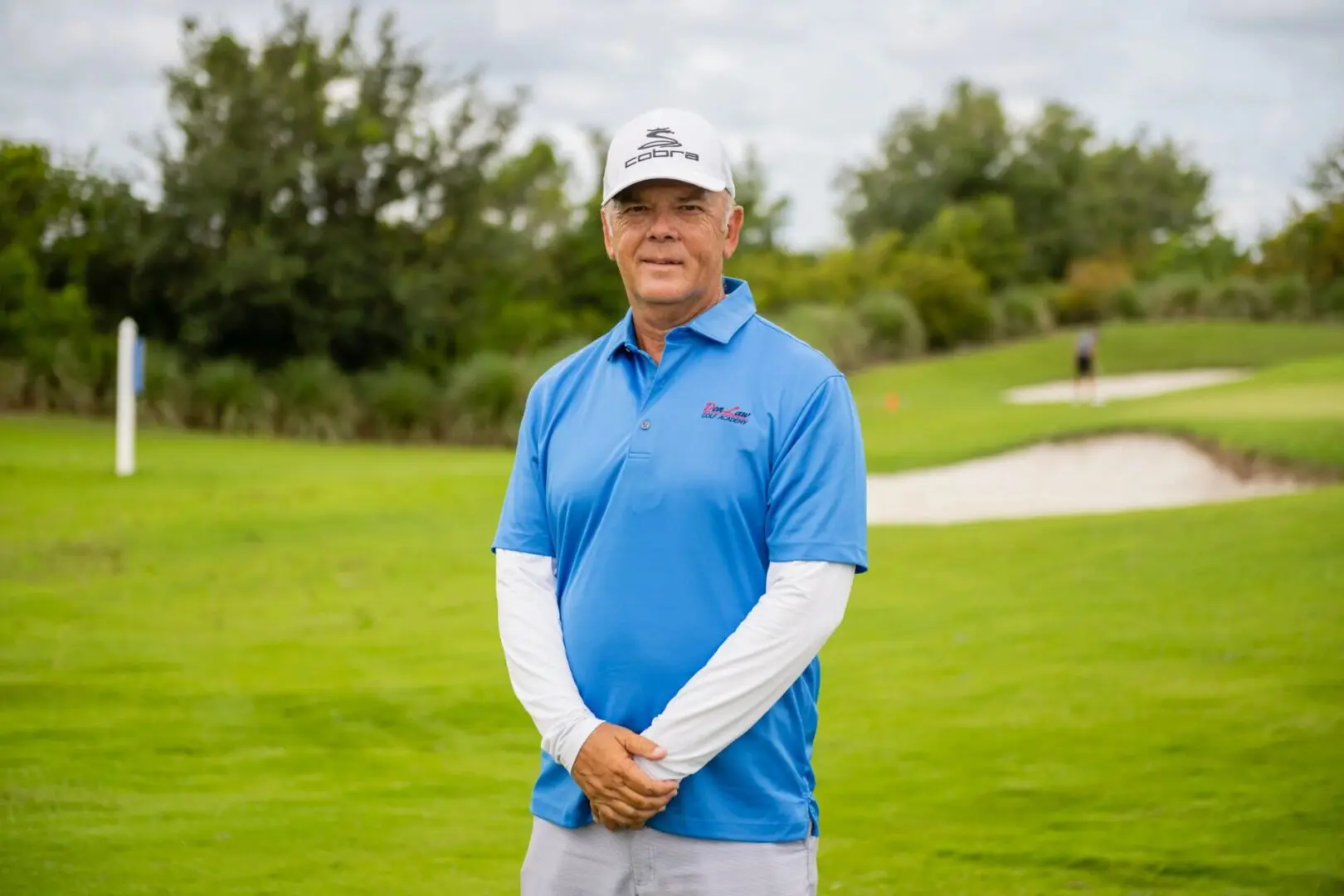 A man in blue shirt standing on grass field.